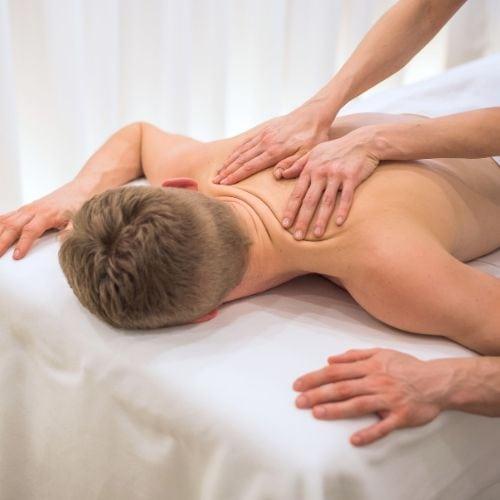 Mężczyzna leżący na kozetce spa podczas masażu sportowego skupiającego się na obszarze karku i szyi